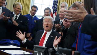 Donald Trump under sin tid som USA:s president. Fotot är taget i Ovala Rummet i Vita huset, efter att Trump har signerat en ökad budget för Nasa. Runt honom applåderar politiker och representanter för rymdmyndigheten.